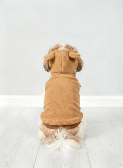 Dog wearing a brown dog coat with ears on a light gray floor and background